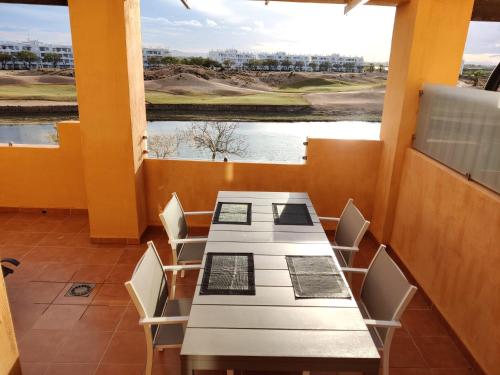 una mesa y sillas en una habitación con vistas a un campo de golf en Apartment La Isla Terrazas de la Torre I, en Roldán