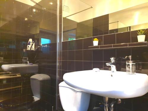 ein Badezimmer mit einem Waschbecken, einem WC und einem Spiegel in der Unterkunft Cosy Studio with Private Parking in Hamburg