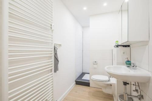 een witte badkamer met een wastafel en een toilet bij Schickes zwei Zimmer Apartment Kostenl Parkm auf der Strasse in Hamburg