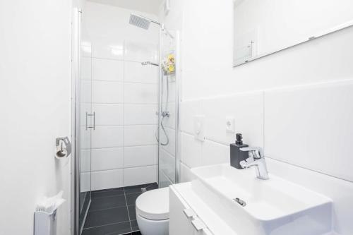 een witte badkamer met een wastafel en een douche bij Charming Apartment in prime location in Hamburg
