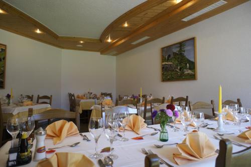 a dining room with white tables and chairs with wine glasses at Aktiv- und Genusshotel Alpenblick in Fiesch