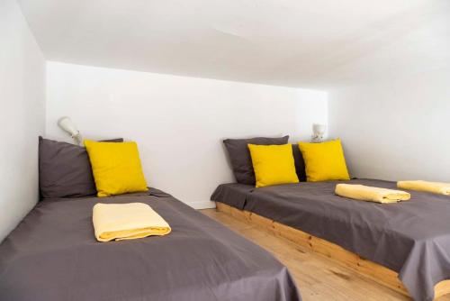 2 Betten mit gelben Kissen in einem Zimmer in der Unterkunft Industrial Style plus Self Checkin plus Street Parking in Berlin