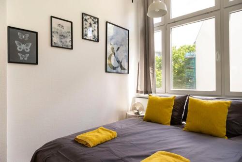 een slaapkamer met een bed met gele kussens en een raam bij Central Big Apartment Self Checkin in Berlijn