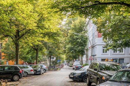 una calle arbolada con autos estacionados en la carretera en Apartment 1 Hamburg Winterhude, en Hamburgo