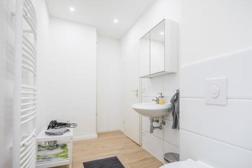 uma casa de banho branca com um lavatório e um espelho em Spacious Two BR Close To Stadtpark and Street Parking em Hamburgo