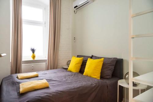 Un dormitorio con una cama con almohadas amarillas y una ventana en Cosy Three BR Two BTH plus AC plus Self CheckIn plus Street Parking, en Berlín