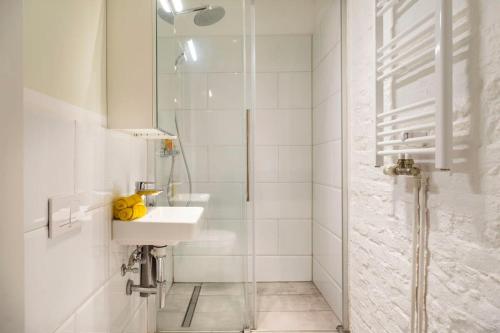 uma casa de banho branca com um lavatório e um chuveiro em Cosy Three BR Two BTH plus AC plus Self CheckIn plus Street Parking em Berlim