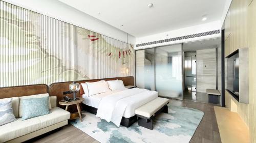 a bedroom with a white bed and a couch at The Westin Yantai in Yantai