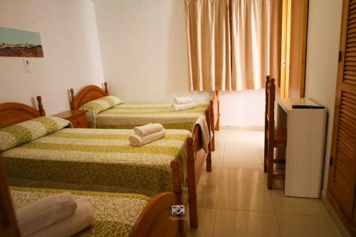 Habitación de hotel con 2 camas y toallas. en Hospedium Hostal Ben Nassar en Arjona