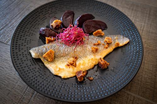 a black plate with a piece of fish and other foods at Hôtel L'Escale Marine Valdys Resort & SPA in Douarnenez