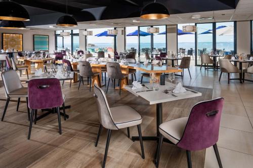 un restaurant avec des tables, des chaises et des fenêtres dans l'établissement Hôtel Valdys Thalasso & Spa - l'Escale marine, à Douarnenez