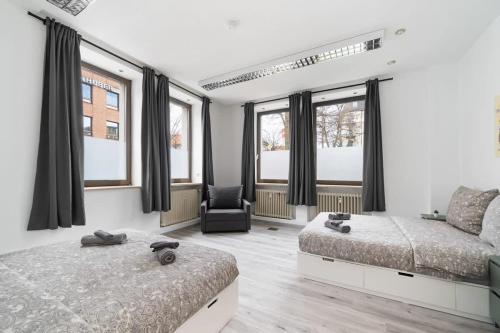 a bedroom with two beds and a chair and windows at 90m2 für bis zu 12 Personen - München Innenstadt in Munich