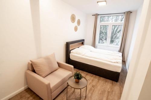 ハンブルクにあるHamburg Gem for 12のベッド1台、椅子、窓が備わる小さな客室です。