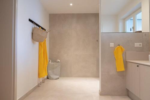 a bathroom with a shower with yellow towels and a sink at Spacious 3-bedroom apartment near Eilbekpark in Hamburg