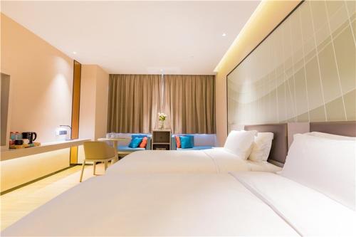 a hotel room with two beds and a living room at The Skytel Hotel Shenzhen International Convention and Exhibition Center in Shenzhen