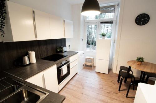 une cuisine avec des placards blancs, une table et une salle à manger dans l'établissement Great Three Bedroom Apartment, à Hambourg