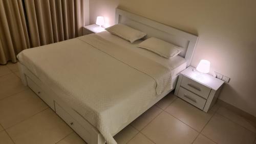een slaapkamer met een bed met twee lampen erop bij Muscat Alqurum apartment in Wuţayyah