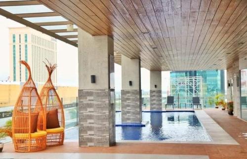 een groot binnenzwembad met stoelen in een gebouw bij Condo Unit with Balcony @ Sunvida across SM City in Carreta