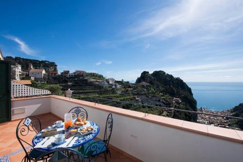 Donna Luisa Suites 19 Amalfi view - free parking في Pontone: طاولة على شرفة مطلة على المحيط