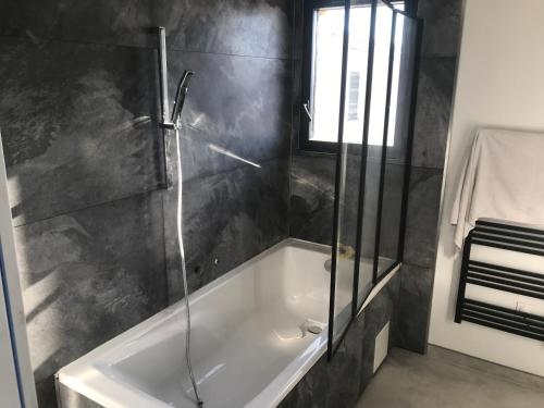 une salle de bain avec baignoire et douche en verre dans l'établissement Villa 110 m2 entre vignoble et mer, à Marseillan