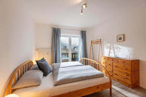 a bedroom with a bed and a dresser and a window at Ferienwohnung Bergpanorama in Oberaudorf