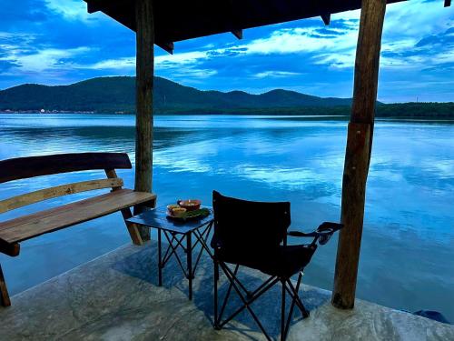 a table and a chair sitting on the edge of a lake at HomeSatay Songpeenong โฮมสเตย์สองพี่น้อง in Chumphon