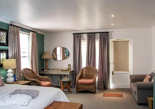 a bedroom with a bed and chairs and a desk at Via's Guesthouse in Greyton