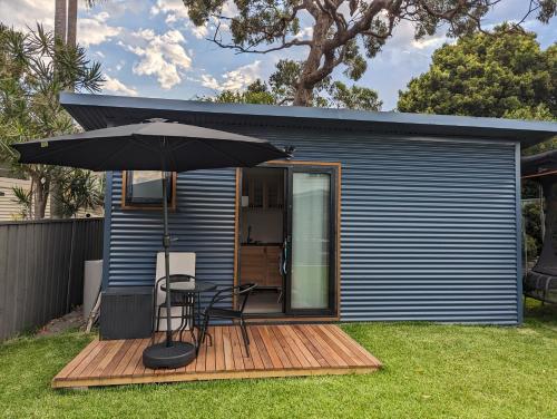 a house with a table and an umbrella on a deck at The shed in Bundeena