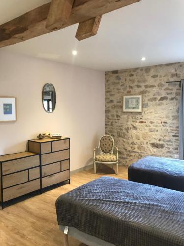 une chambre avec deux lits et un mur en pierre dans l'établissement Villa, vieille ferme rénovée calme, nature avec piscine privée., à Vindrac-Alayrac