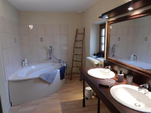 a bathroom with two sinks and a tub and a mirror at Le Puy Maury in Augne