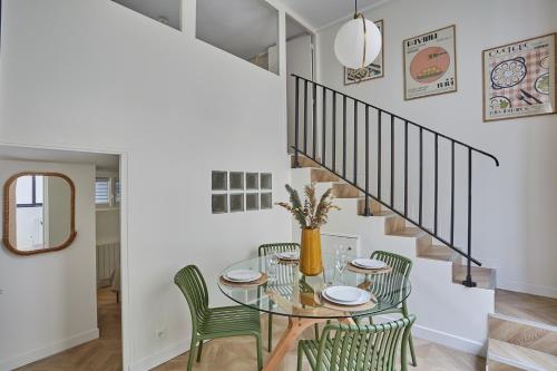 une salle à manger avec une table en verre et des chaises vertes dans l'établissement Apartment Saint Germain des prés by Studio prestige, à Paris
