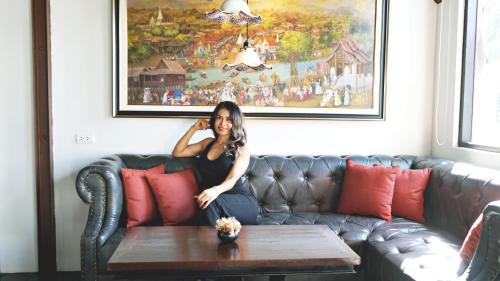 a woman sitting on a couch with a coffee table at Buri Sriping Riverside Resort & Spa in Chiang Mai