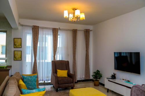 a living room with a couch and a tv at Spring Garden By Edmor Suites in Nairobi