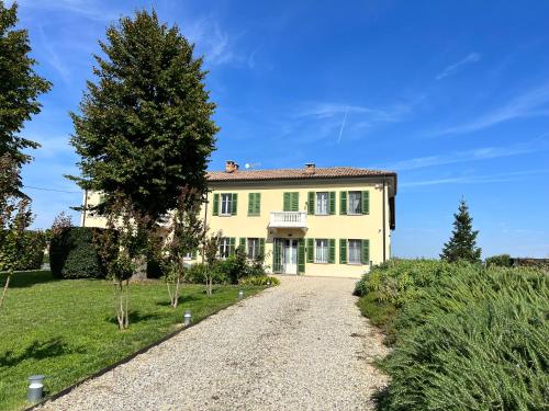 a large yellow house with a gravel driveway at Belcasale in Vignale Monferrato