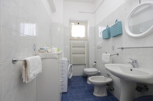 uma casa de banho branca com um lavatório e um WC em La Coccinella Sorrento em Sorrento