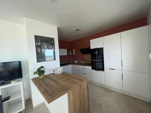 une cuisine avec des armoires blanches et une table en bois dans l'établissement CARNON - T4 1ére ligne, à Mauguio