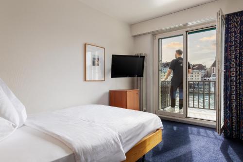 um homem olhando pela janela de um quarto de hotel em Merian Basel - Self Check-in em Basileia