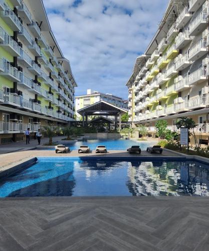 einem Pool in der Mitte von zwei Apartmentgebäuden in der Unterkunft Condo Azur Suites A326 Amani Resorts Residences , 5 minutes Airport, Netflix, Stylish, Cozy with Luxurious Swimming Pool in Pusok