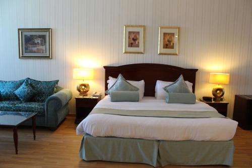 um quarto de hotel com uma cama grande e um sofá em Swiss International Al Hamra Hotel em Dammam