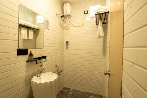 a white bathroom with a sink and a shower at Click Hotel Mundra in Mundra