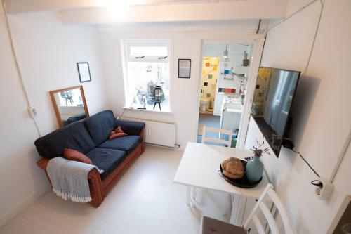 een woonkamer met een blauwe bank en een tafel bij Zomerhuisje Wijk aan Zee in Wijk aan Zee