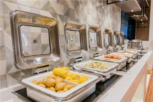 a row of trays of food on a buffet line at The Skytel Hotel Shenzhen International Convention and Exhibition Center in Shenzhen