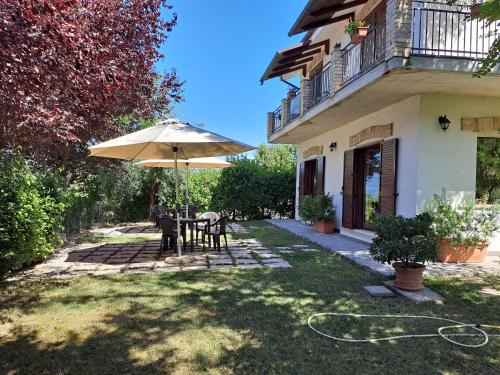 un patio con una mesa y una sombrilla frente a una casa en Agriturismo Fattoria colle Luca, en Moscufo