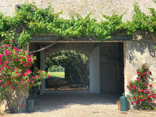 une entrée à un bâtiment avec des fleurs roses dans l'établissement L échappée belle en campagne charentaise, à Gondeville