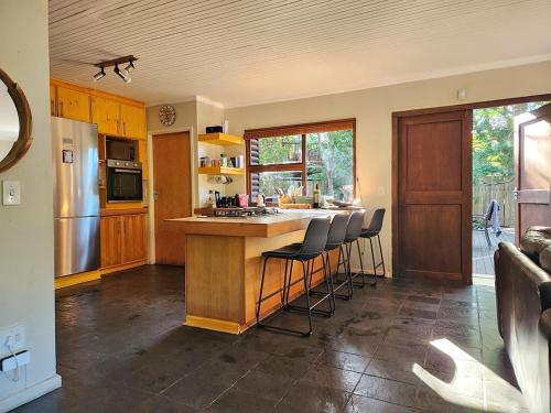 una cucina con bancone e sgabelli di Nature's Edge Cabin a Natureʼs Valley