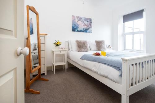 a white bedroom with a bed and a mirror at Marian Cottage in Ingleton