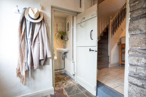 a hallway with a white door and a hat on the wall at Marian Cottage in Ingleton
