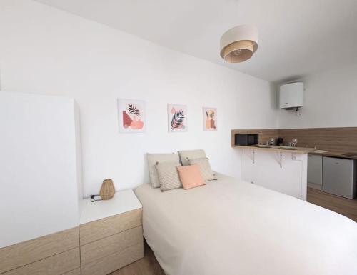 a white bedroom with a white bed and a kitchen at Rouen Centre historique in Rouen