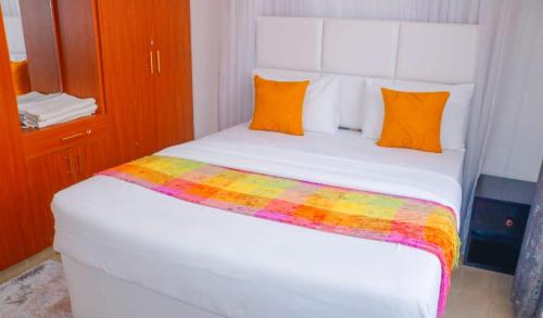 um quarto com uma cama branca e um cobertor colorido em Janos Luxury em Kisumu