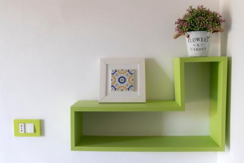 a green shelf with a picture and a plant on it at La Vittoria in Lido di Ostia